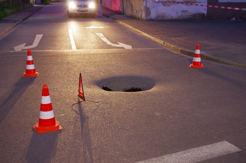 Kanaleinbrauch - ein kleines Loch tut sich in der Straßendecke auf.